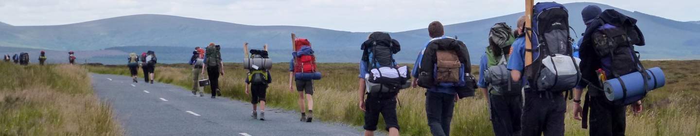 Wandernde Pfadfinderinnen und Pfadfinder entlang einer Straße in Irland 2012.